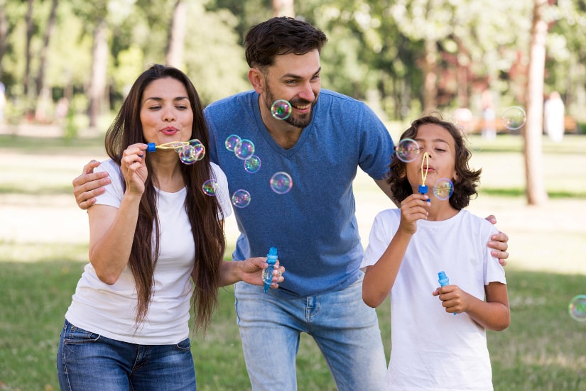 Parents having fun with kid blowing bubbles