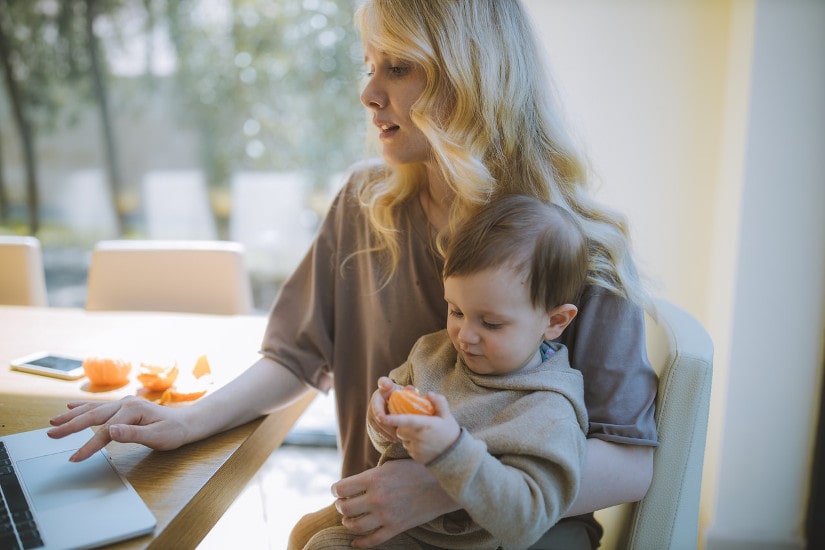 Mom holding son in lap while working on laptop