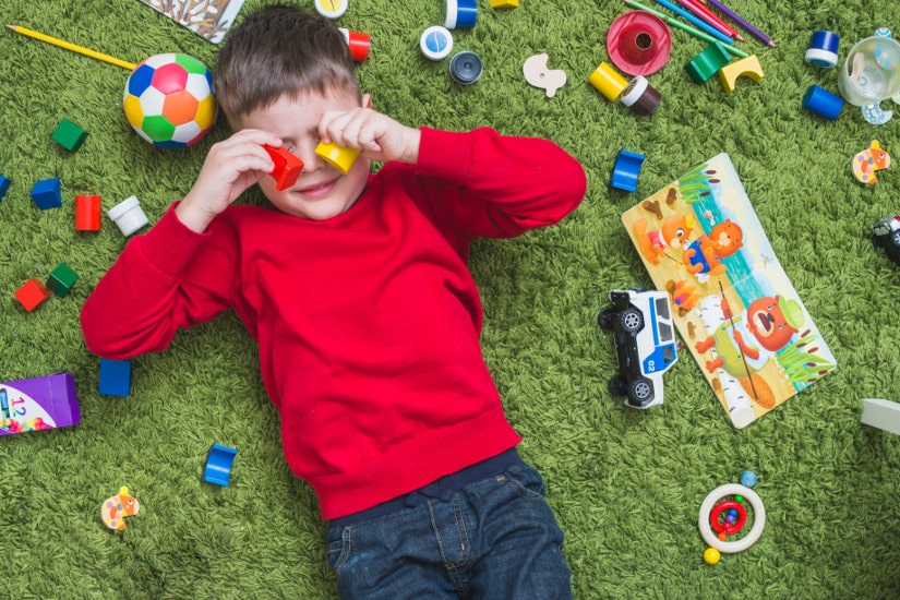 Boy lying in toy mess