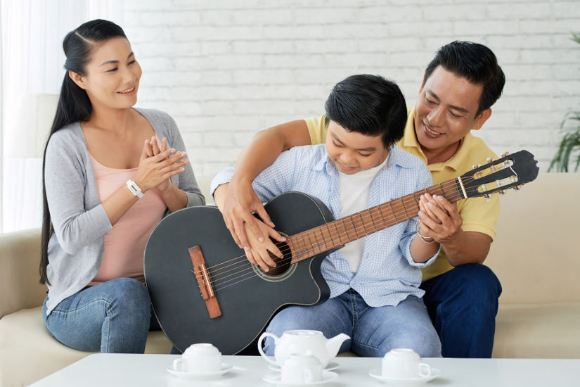 Dad teaching guiter to son