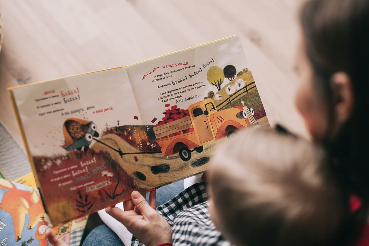 Child listening to story sitting in mom’s lap